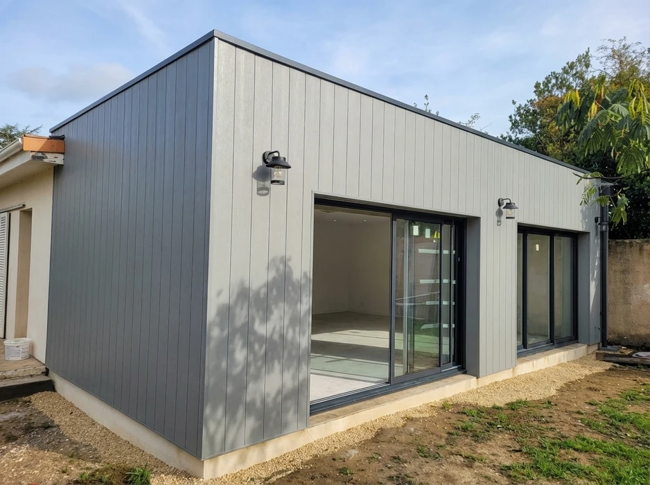 Ouvrier installant un système électrique dans une construction en bois, travaillant depuis un escabeau dans un espace intérieur avec ossature bois et isolation
