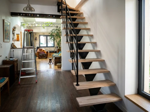 Chantier de construction résidentielle avec architecte ou contremaître en casque blanc et salopette bleue présentant des plans à un couple de clients