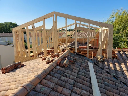 Une personne remplit un formulaire administratif français de demande d'autorisation de construire, écrivant "Extension" au marqueur bleu dans la section "Nature du projet"