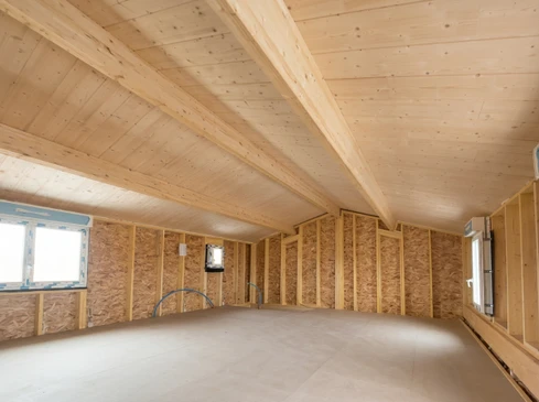 Surélévation d'une maison individuelle avec bardage horizontal en PVC gris, fenêtres à volets roulants blancs et œil-de-bœuf circulaire