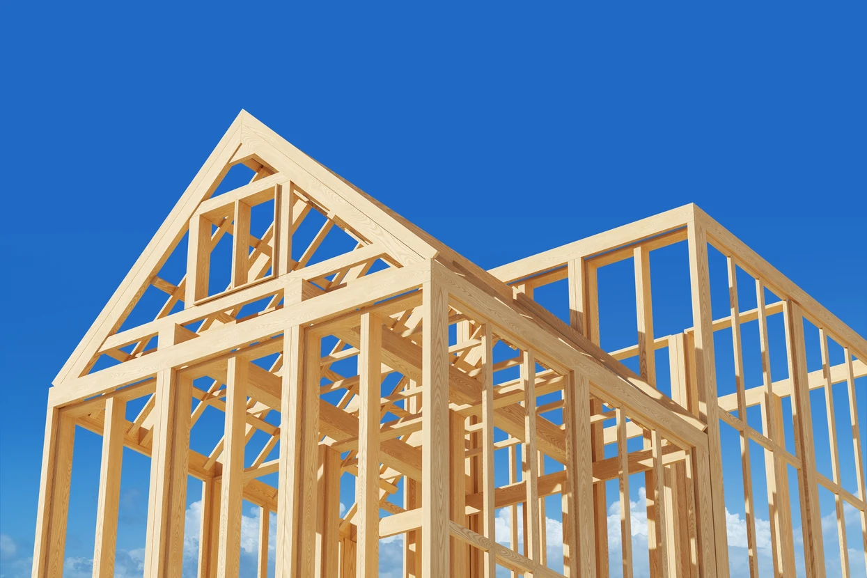 Chantier de construction résidentielle en cours, structure en bois apparent sous ciel bleu avec effet de lumière dorée