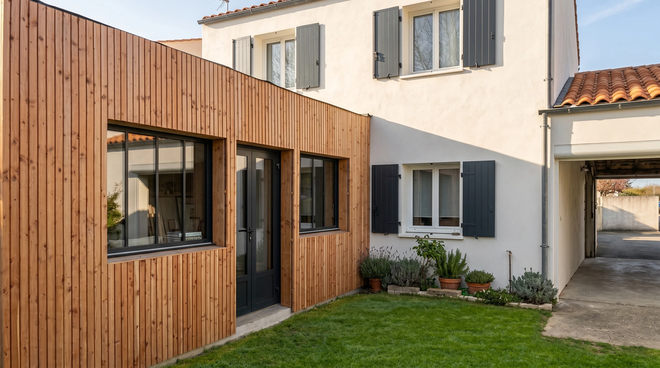 Extension moderne en bois avec bardage vertical sur maison traditionnelle en brique