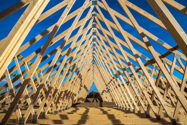 Chantier de construction extérieur avec ouvrier installant une charpente en bois